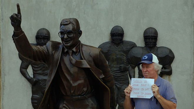 Bernie McCue protests next to the Joe Paterno statue in Happy Valley