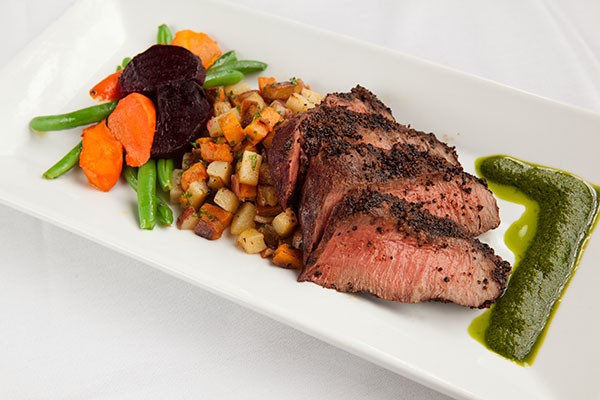 Grilled flat-iron steak with mojo sauce, potato hash and spring vegetable medley