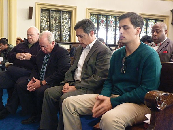 U.S. Congressmen Mike Doyle (second from left) and state Sen. Jay Costa (second from right) bow their heads in a moment of silence for those killed in the Wilkinsburg shootings.