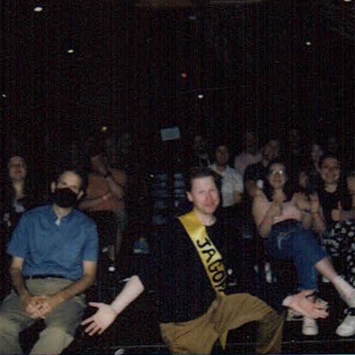 July 1, 2023 Am I the Jagoff? featuring Jerome Fitzgerald. Jerome is posed with the audience wearing a “Jagoff” sash