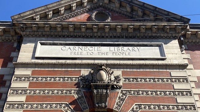 A brick and stone Carnegie Library façade reading "Free to the People."