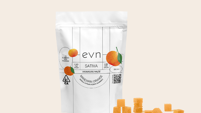 Pale beige background, white bag of Delta 9 gummies that says: "evn sativa Hawaiian haze mandarin orange", with three oranges on the bag, smattering of orange-colored gummies in the foreground