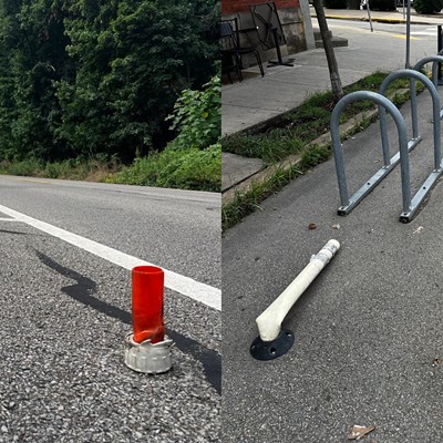 An orange plastic stump where a FlexPost used to be and several smashed posts "protecting" a bike rack