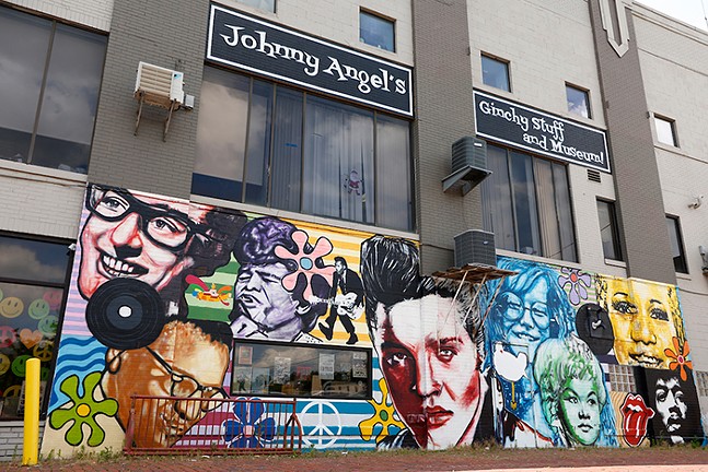 A colorful mural painted on the exterior of Johnny Angel's Gichy Stuff, featuring famous musicians including Chuck Berry, Elvis Presley, Janis Joplin, and Jimi Hendrix