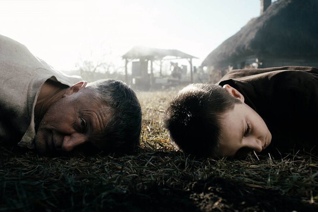 A man and a young boy press their ears to the ground in the Ukrainian film The Guide.