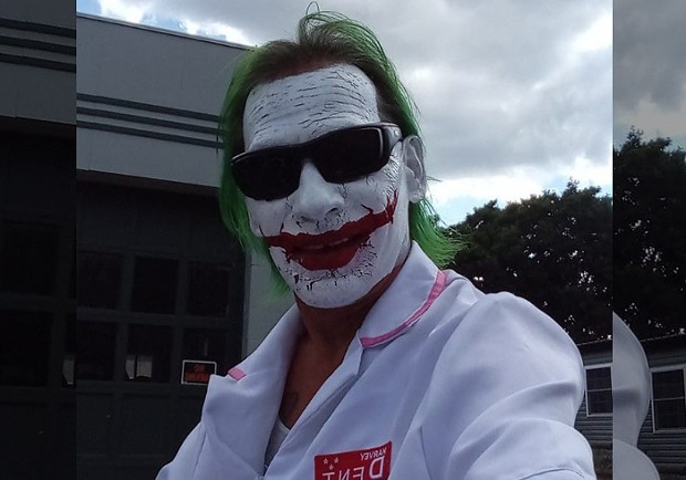 A man dressed up as the Joker, with full make-up and wig
