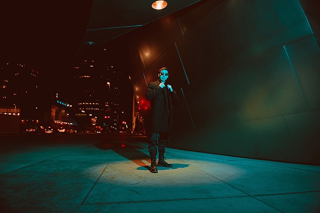 Electronic artist Rinzen poses in a stylishly lit alleyway.