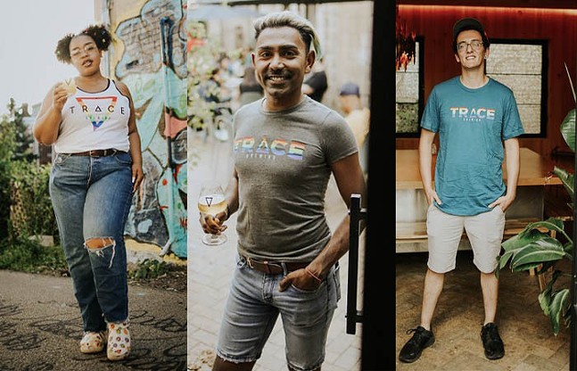 Three people pose in rainbow Pride merch from Trace Brewing