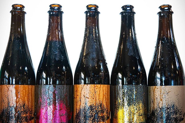 Four beer bottles with colorful labels sit side by side.