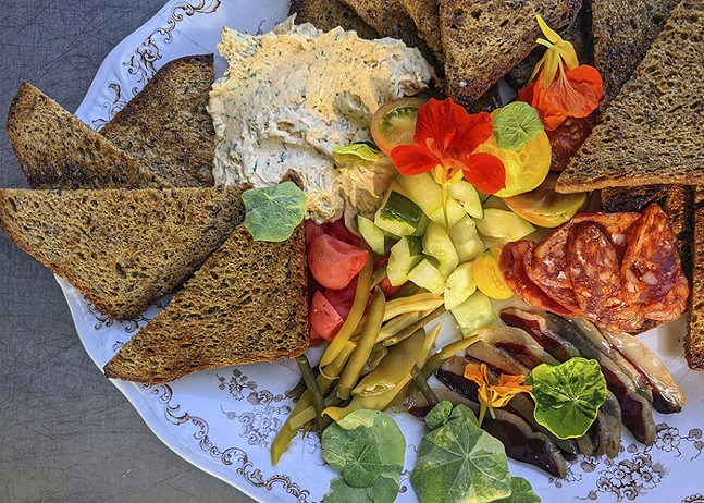 A beautifully plated meal includes triangles of dark bread and bright, multi-colored tomatoes.
