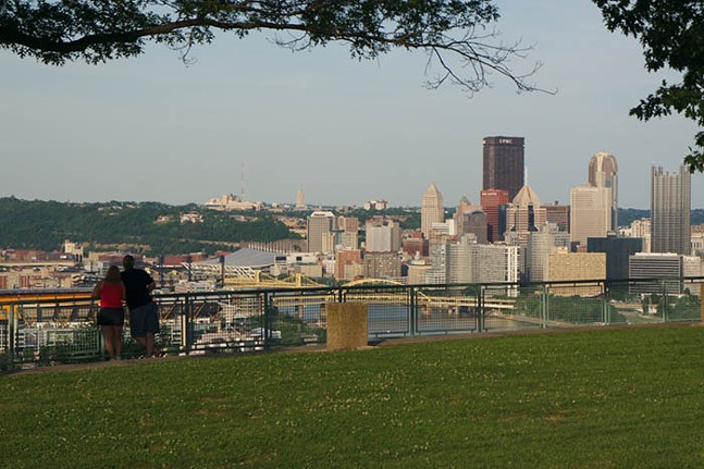 A couple stands next to each other admiring a view of the Pittsburgh skyline