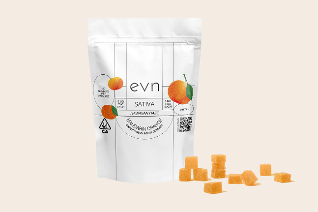 Pale beige background, white bag of Delta 9 gummies that says: "evn sativa Hawaiian haze mandarin orange", with three oranges on the bag, smattering of orange-colored gummies in the foreground