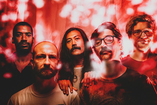 Five band members with different facial hair in a blurry red photo filter