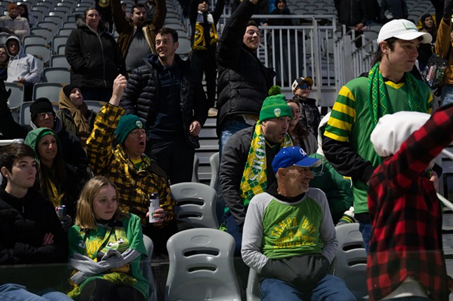 Fans in green and gold cheer on Tampa Bay while bundled against the cold.