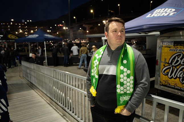 A man with a Rowdies scarf near a Bud Light beer tent.