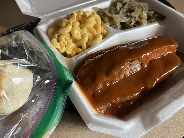 Sauce-slathered ribs in a compartmented tray with cabbage and mac and cheese