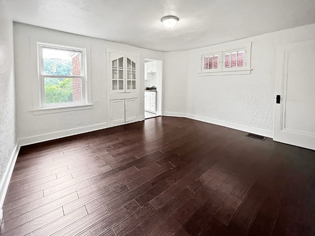 A large white-painted room with a small cabinet built into one wall