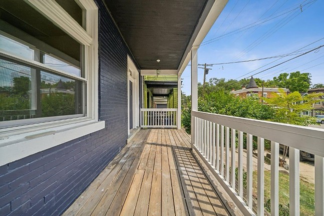 A wide porch with unpainted floorboards