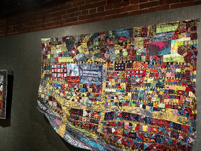 A bright quilt with yellow roads and patches of color representing buildings