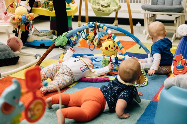 Babies crawl amid colorful toys and soft carpeting