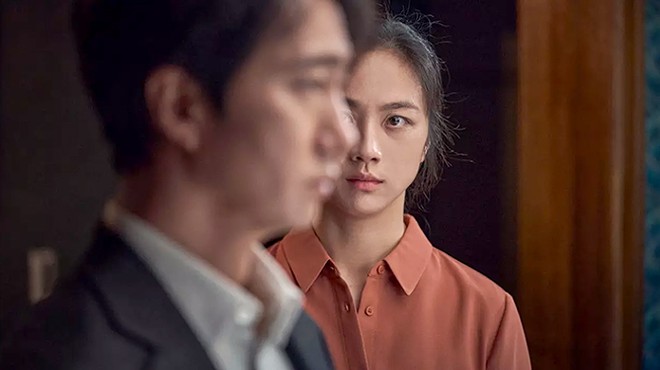 A Korean woman stares at a Korean man in profile, from the movie Decision to Leave