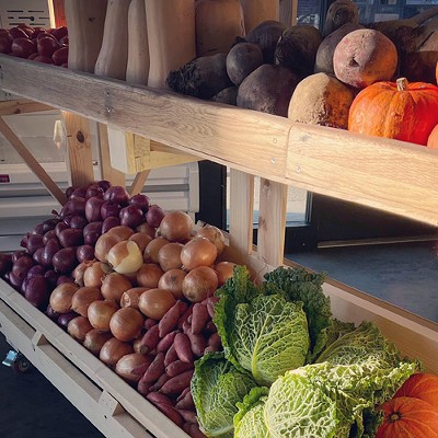 A selection of fresh, colorful produce is carefully arranged on a stand outside a market.
